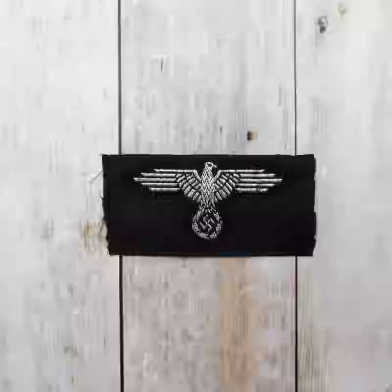 Waffen-SS Officers Cap Eagle Waffen-SS Officers Cap Eagle – Premium Replica, made of Silk-woven silver thread with aluminum wire on black wool background