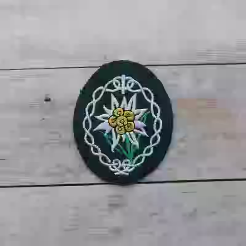 Gebirgsjäger Enlisted Men's Sleeve Cloth Patch Gebirgsjäger Enlisted Men's Sleeve Cloth Patch – Premium Replica, made of Silver, green, and yellow embroidery on darkgreen wool background