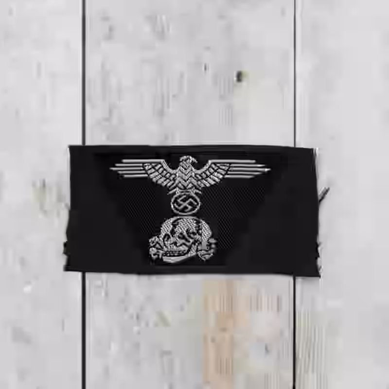 Panzer-SS Officers Woven Trapezoid Cap Insignia Panzer-SS Officers Woven Trapezoid Cap Insignia – Premium Replica, made of Be-Vo woven silver thread on black cotton background